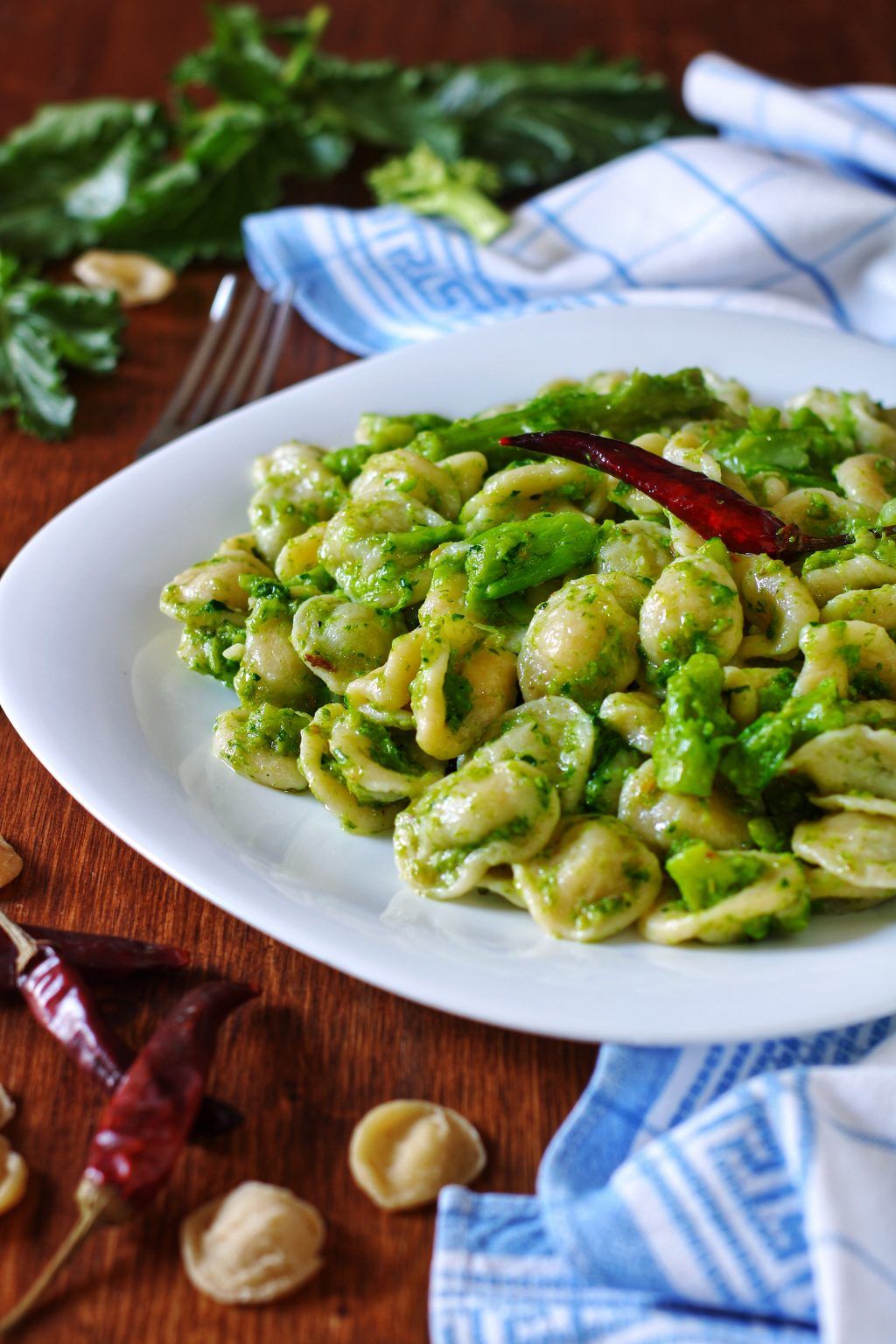 Fresh handmade orecchiette pasta drying on a wooden board in a sunlit alleyway of Bari Vecchia