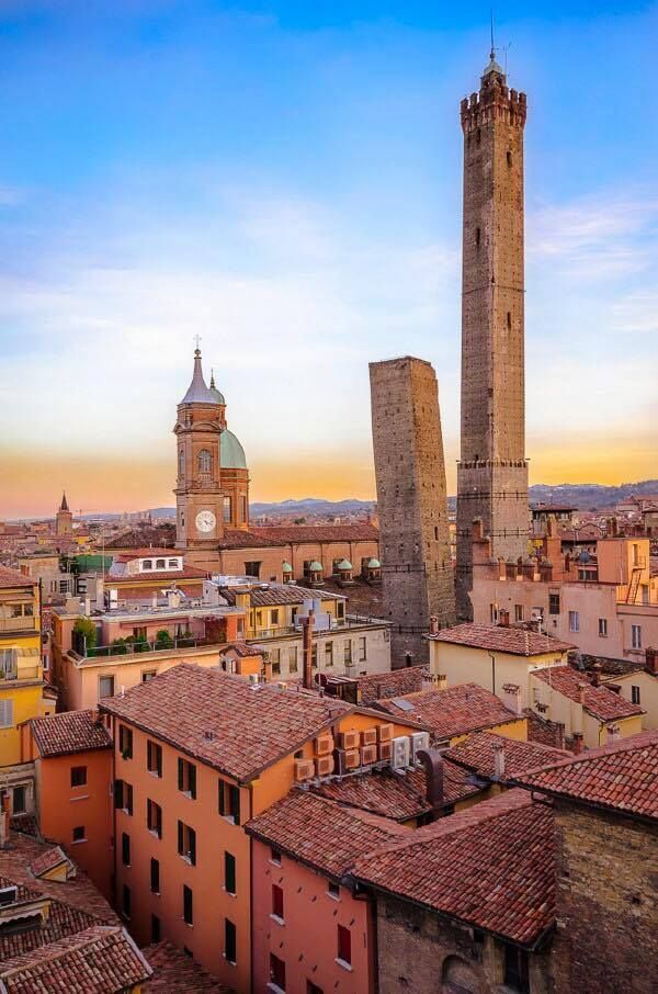 The Two Towers of Bologna at sunset — Asinelli and Garisenda rising above the medieval city's terracotta rooftops