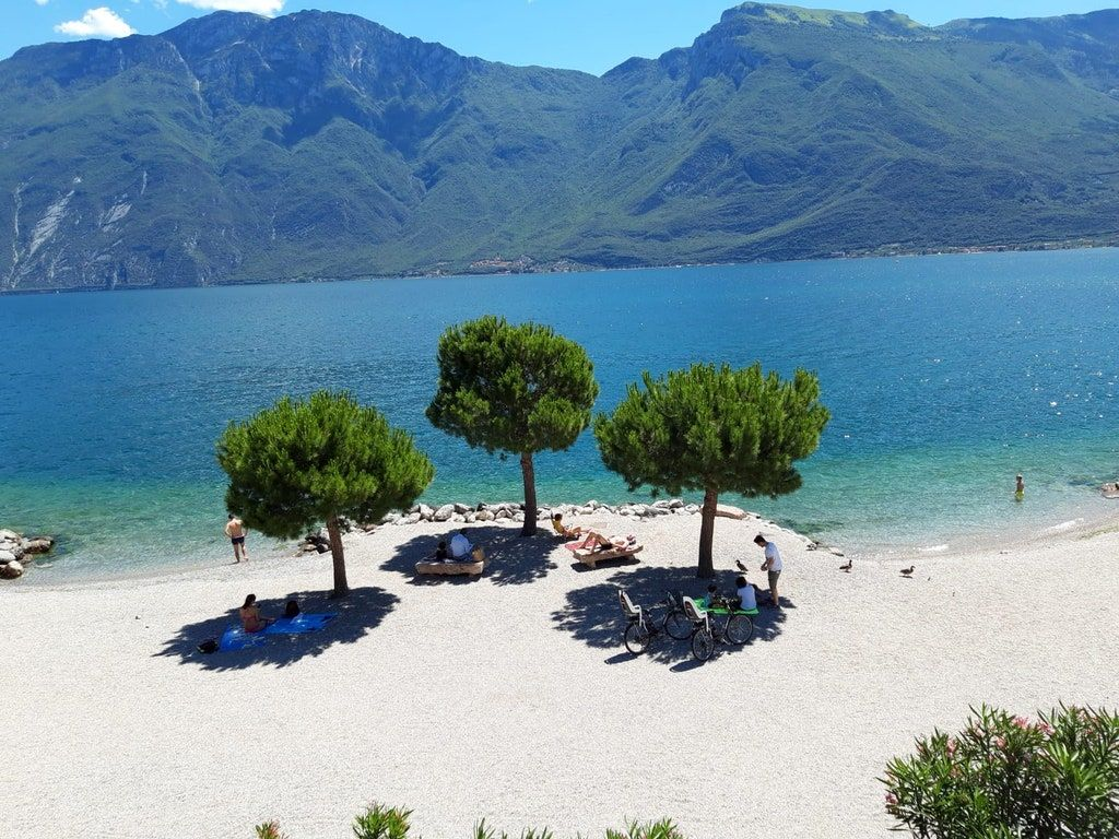 The crystal-clear beaches of Lake Garda, where the turquoise water meets the shingle and sand shores backed by the dramatic mountain landscape of the northern lake