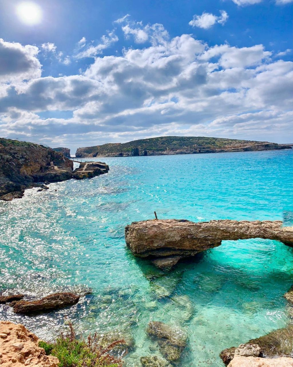 The extraordinary Blue Lagoon of Comino, Malta, its waters an impossibly vivid turquoise over the white sandy bottom in the clear Mediterranean light