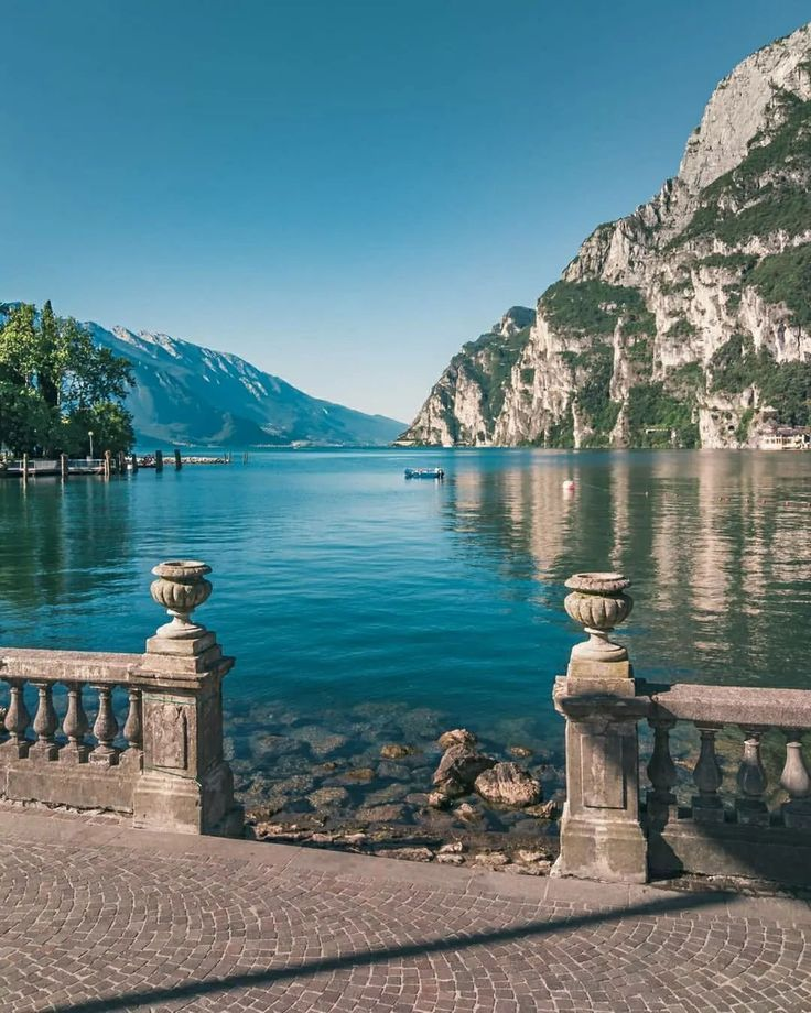 Lake Garda in October with golden autumn colours reflecting on the calm water and mountains in the background