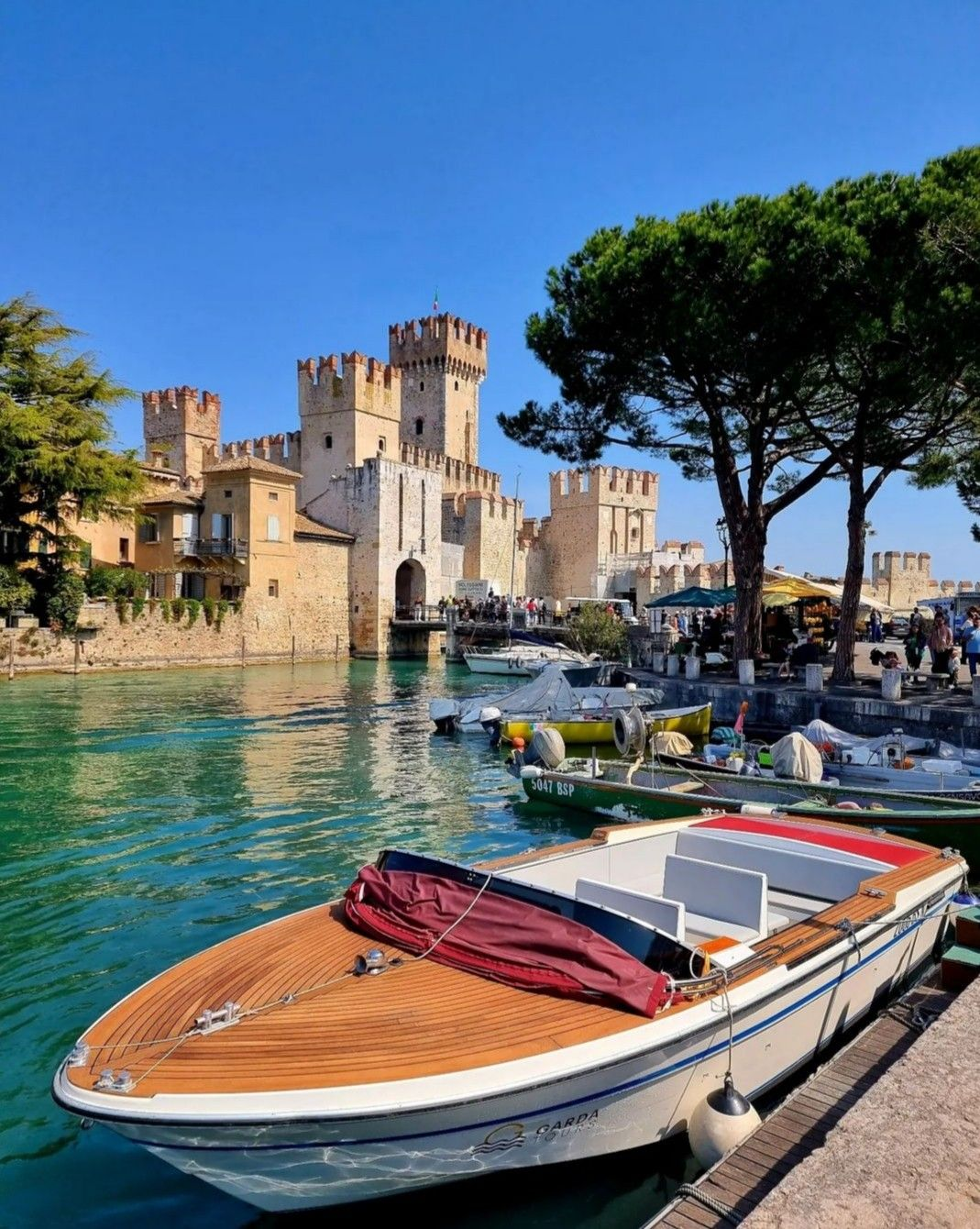 Lake Garda in autumn with golden sunlight reflecting on the calm water and mountains in the background.