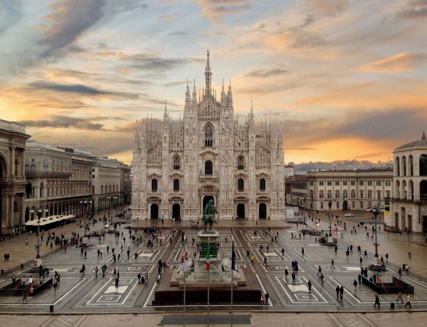 The magnificent Duomo di Milano seen from the Galleria Vittorio Emanuele II, with golden hour light illuminating the marble facade.