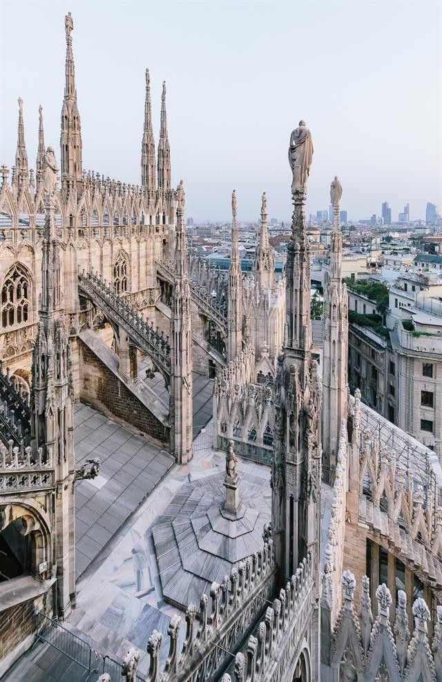 The rooftop of Milan's Duomo with its famous Madonnina statue gleaming in the sunset light.