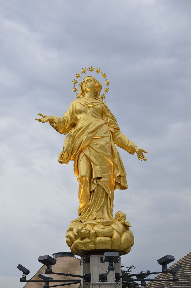 The rooftop of Milan's Duomo with the golden Madonnina statue against a dramatic sky.