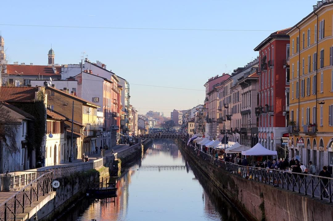 The Naviglio Grande canal in Milan at sunset, with lights beginning to reflect on the dark water.