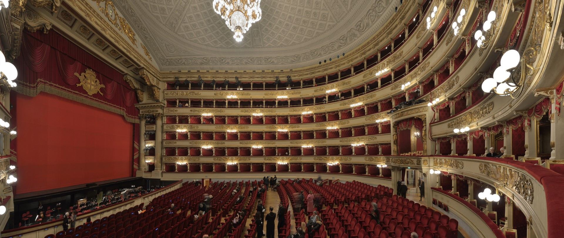 The neoclassical facade of Teatro alla Scala in Milan, with the monument to Leonardo da Vinci in the foreground.