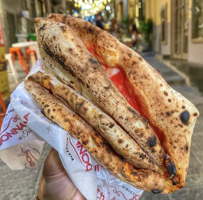 A golden, crisp fried pizza being cut open, steam rising from the melted ricotta and salami filling inside the puffy crust.