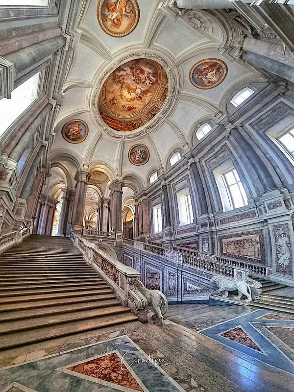 The magnificent Scalone Reale, the grand staircase of the Royal Palace of Caserta, with its white marble steps and central equestrian statue.