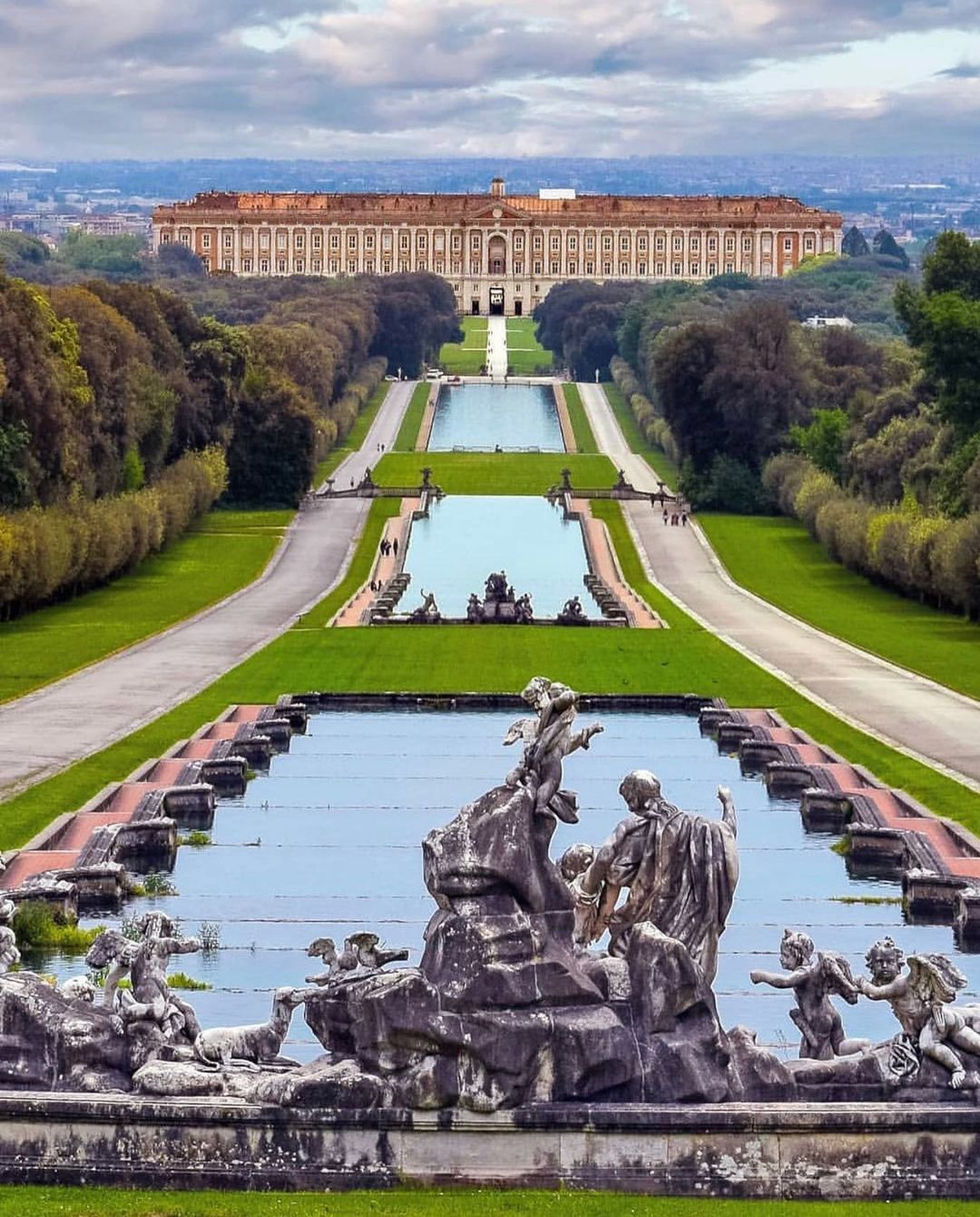 The majestic facade of the Royal Palace of Caserta, the largest royal residence in the world by volume, with its grand staircase and sweeping gardens.