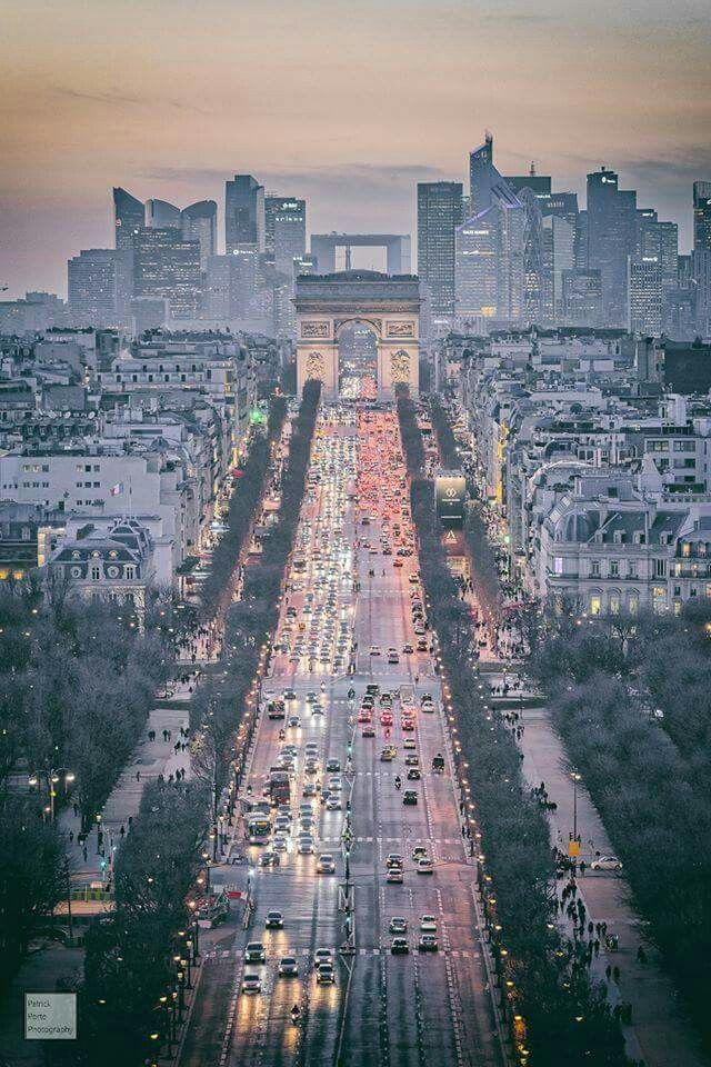 The Arc de Triomphe at the western end of the Champs-Élysées, framed by autumn trees and the evening sky.