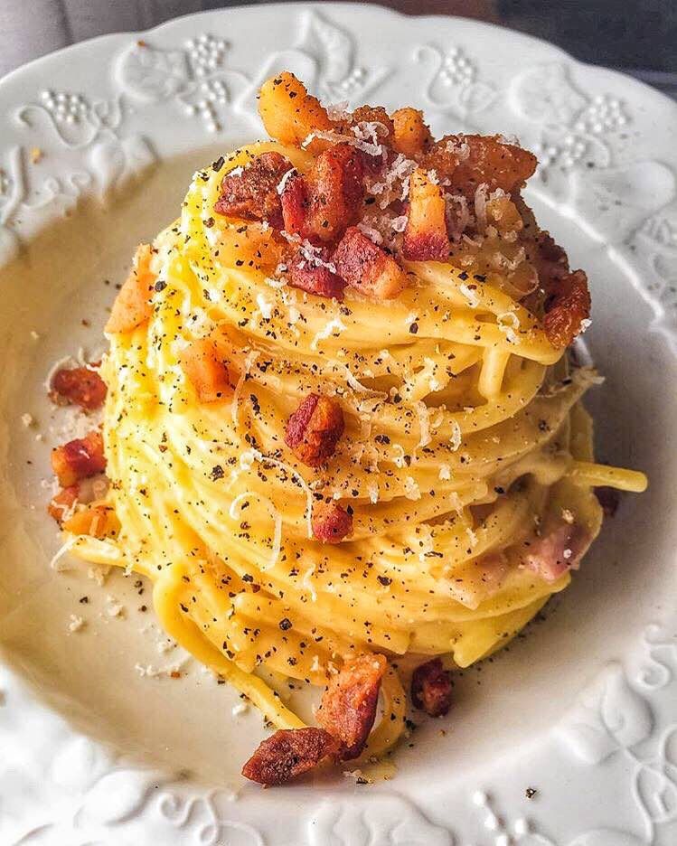 A serving of pasta alla carbonara with crispy guanciale and a generous dusting of pecorino romano