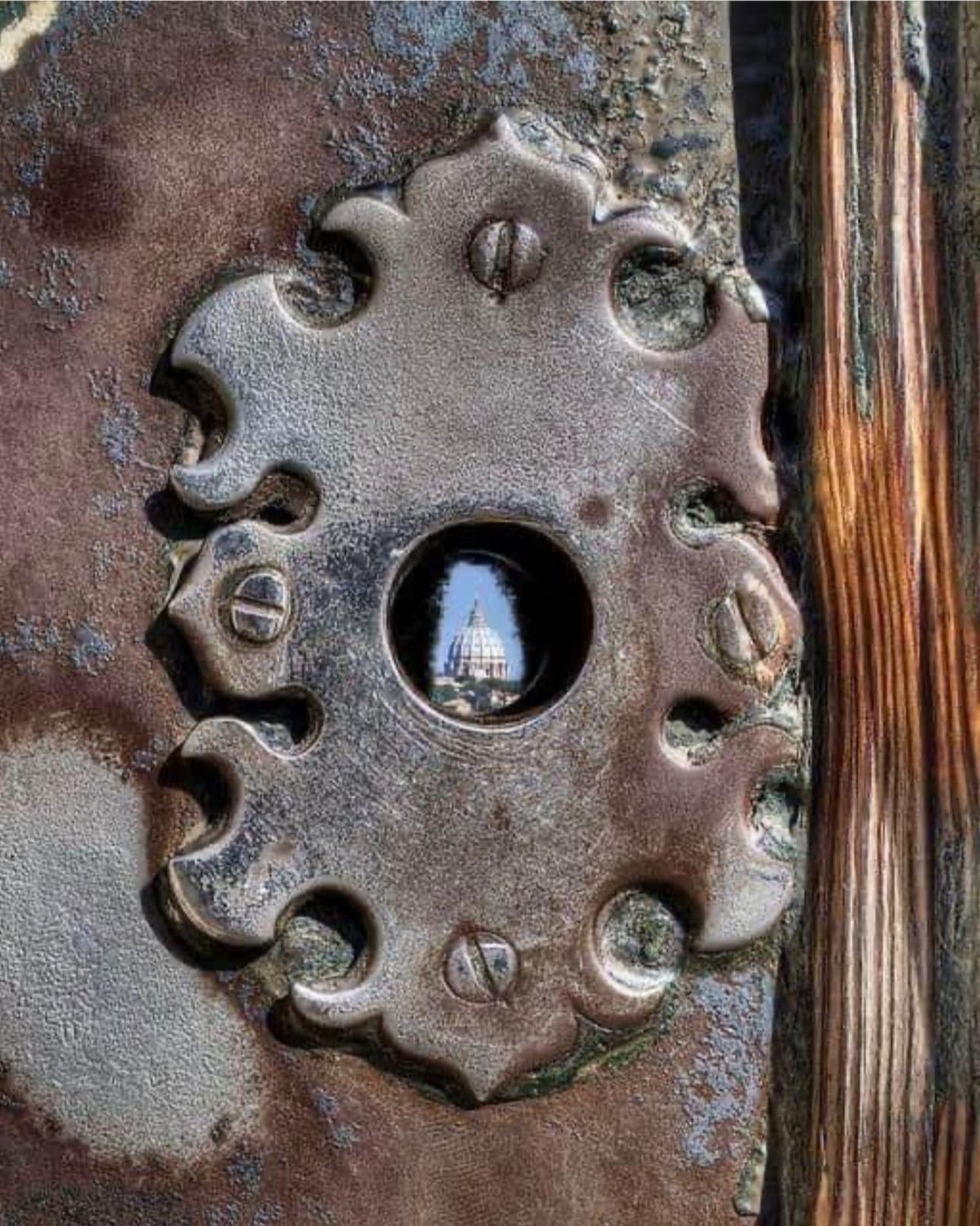 The famous Aventine keyhole in Rome, framing the dome of Saint Peter's Basilica through a cypress avenue