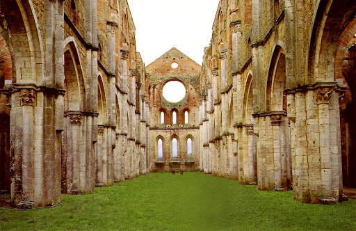 The majestic roofless nave of San Galgano Abbey in Tuscany, with Gothic arches framing the sky above