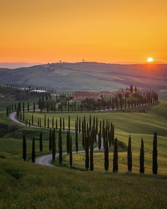 The Val d\'Orcia valley in Tuscany in autumn — golden hills, cypress trees and a medieval farmhouse