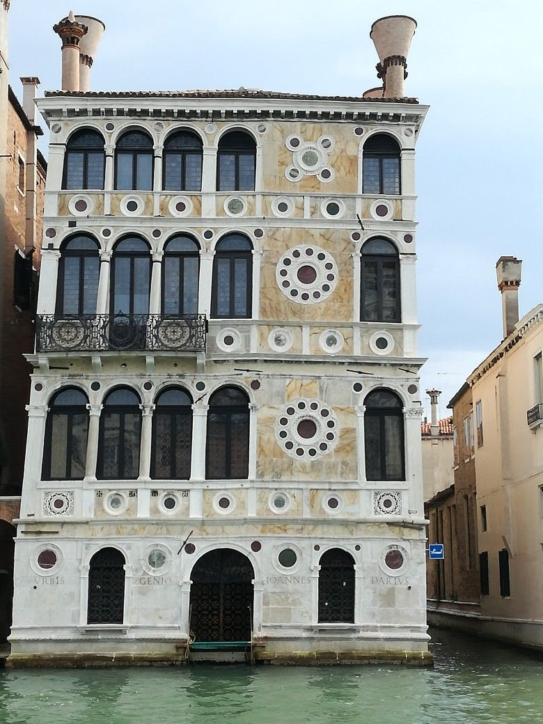 The exquisite Gothic facade of Ca' Dario reflected in the waters of the Grand Canal in Venice, Italy